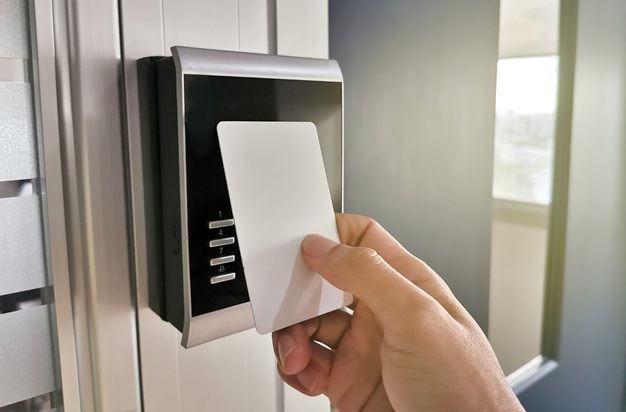 someone holding up their work badge to an advance security card reader